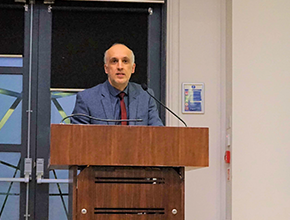 Professor stands at podium while he delivers lecture